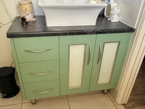 Bathroom vanity before resurfacing, with green cabinetry and a dark benchtop